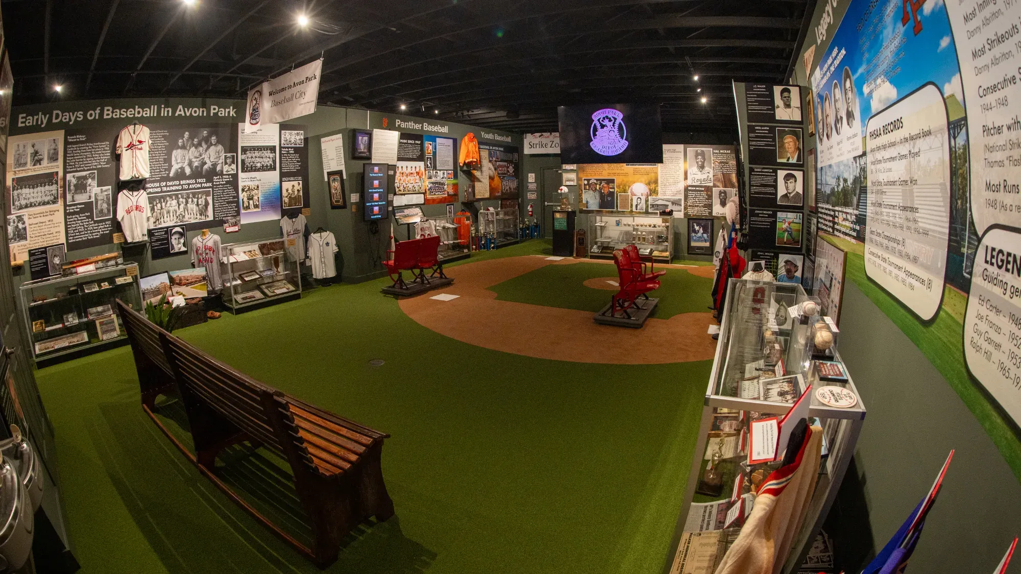 Wide interior view of the Avon Park Baseball Museum showing the turf infield and exhibit walls