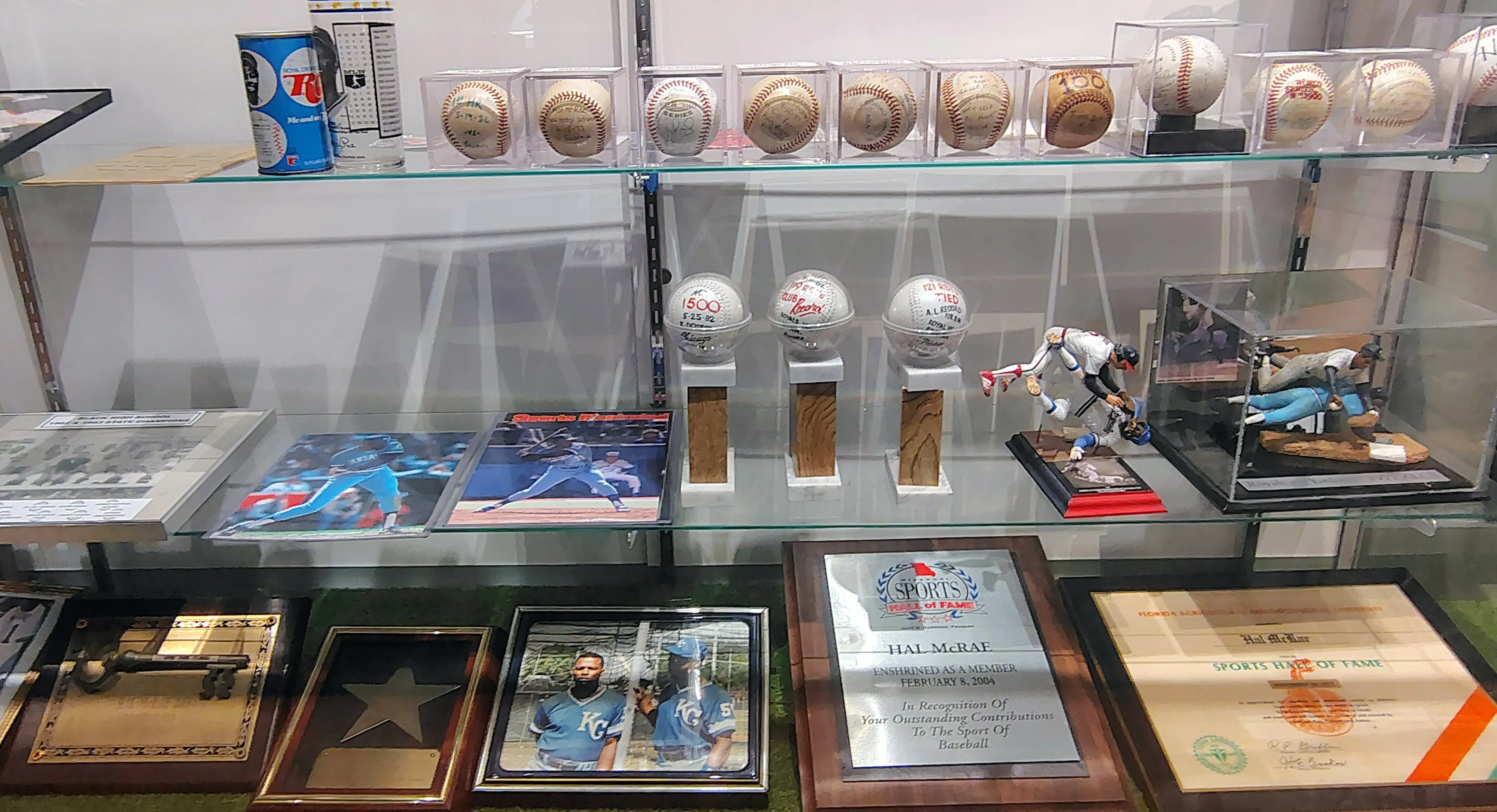Glass display case with autographed baseballs, awards, and Kansas City Royals memorabilia honoring Hal McRae.