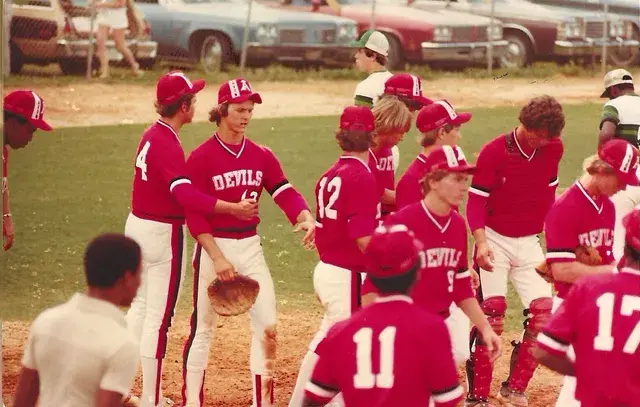 The Devils gather on the field after a game, players in red jerseys numbered 4, 12, 9, 11 and 17 shaking hands.