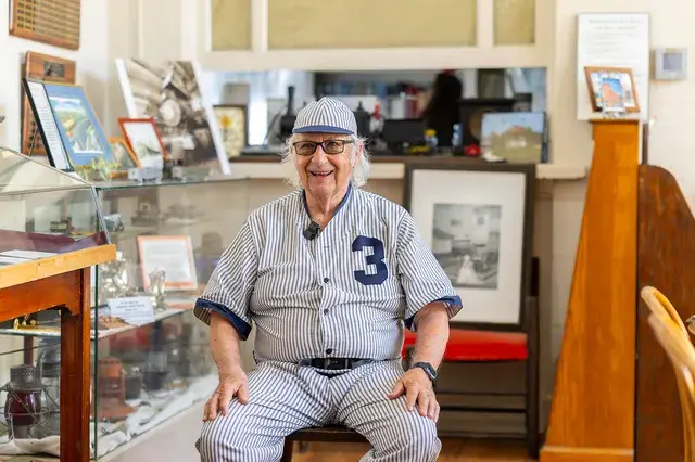 The man in the vintage pinstriped number 3 uniform and cap sits for an interview in the Depot office.