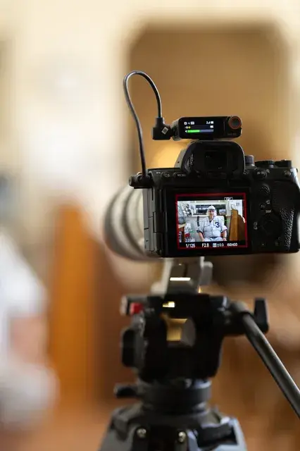A camera on a tripod records the interview.