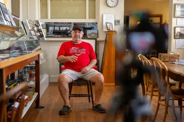 A man in a red shirt sits for an interview in the Depot office.