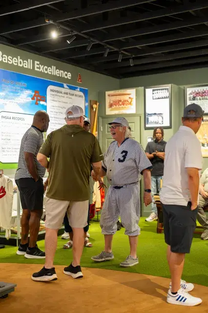 Guests, the man in the vintage pinstriped number 3 uniform among them, examine the panels.