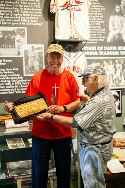 The two men with the framed plaque, smiling.