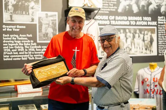 The framed plaque held up between the two men, closer.
