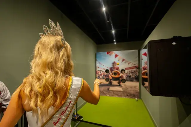 A young woman in a crown and sash tries the pitching game.