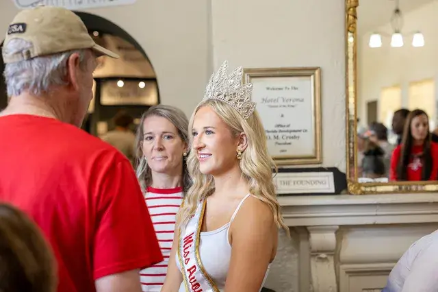 A young woman in a crown and Miss Avon Park sash in the Depot lobby.