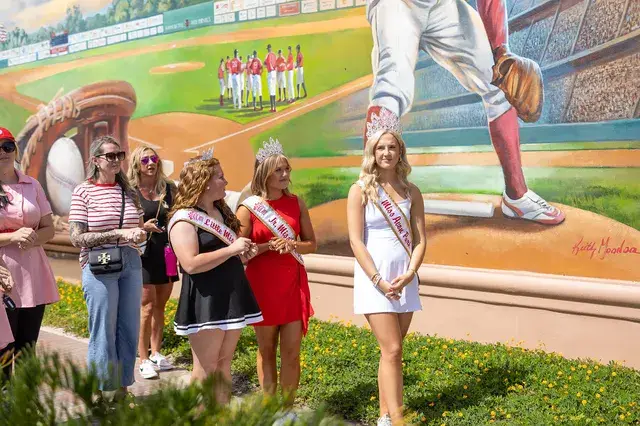 Pageant winners pose in front of the mural.