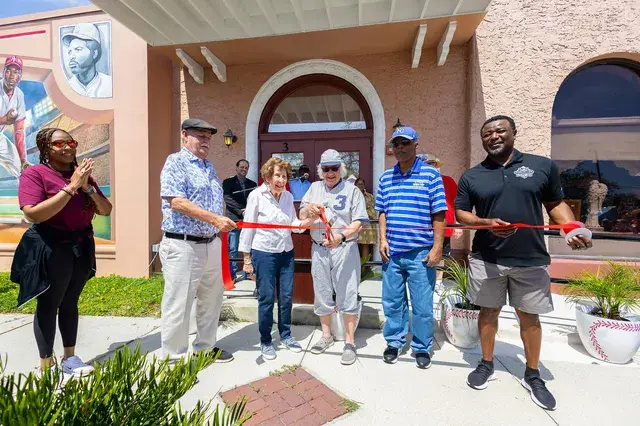 Officials cut a red ribbon in front of the Depot entrance with oversized scissors.