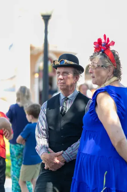 A couple in period costume, a top hat and a blue gown.