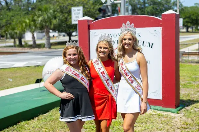 The pageant winners at the sign, closer.