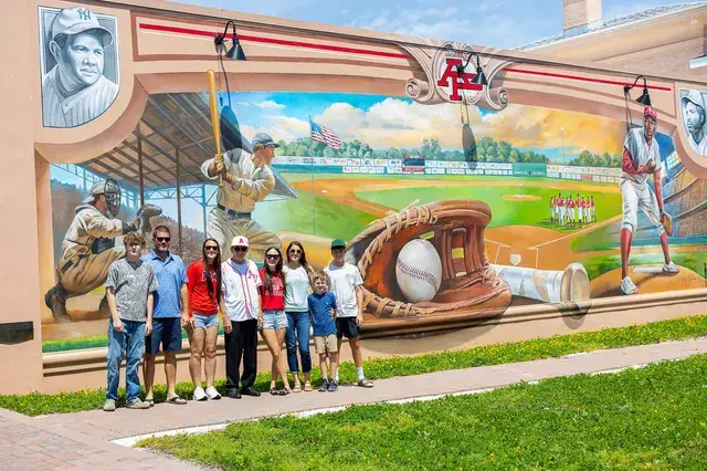 A family poses in front of the mural.