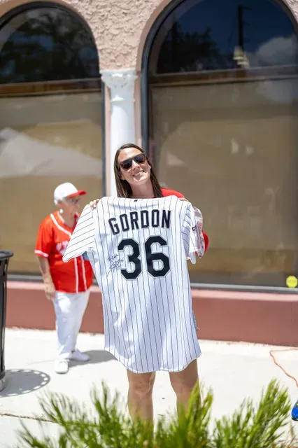 A woman holds up a red-and-white Gordon 36 Boston jersey at the museum opening.