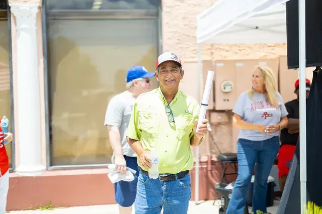 A man in a yellow shirt holds a rolled poster.