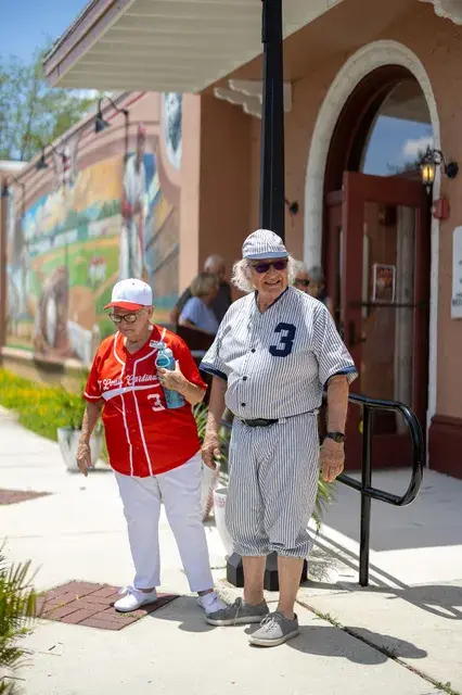 Two people in uniform walk from the Depot entrance, one of them the man in the vintage pinstriped number 3 uniform.