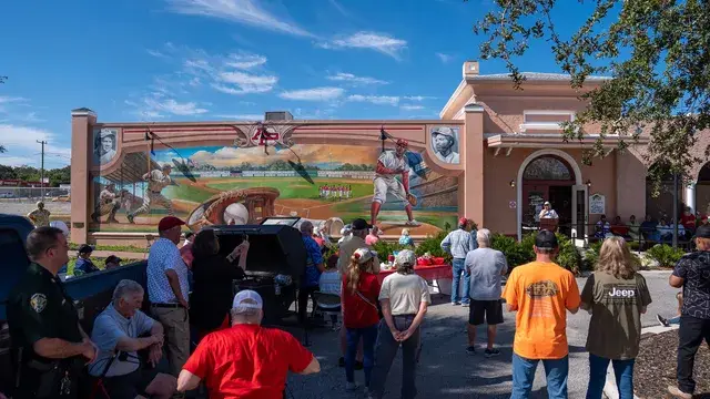 Guests, a sheriff's deputy among them, face the mural and the podium at the Depot entrance.
