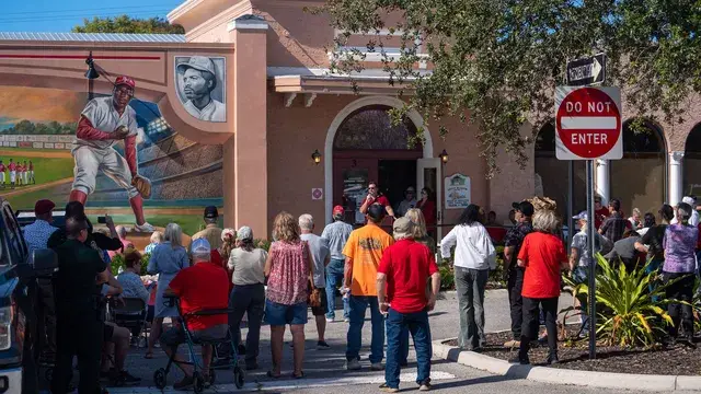 Guests gathered on the pavement in front of the mural, a Do Not Enter sign at the corner.