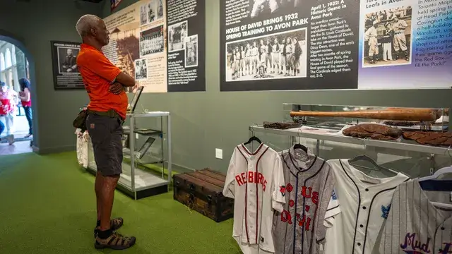 A visitor studies a display of vintage jerseys and a wall of team photographs.