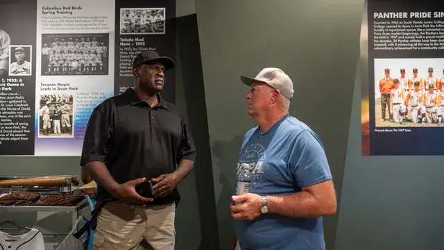 Two men talk beside panels on the Toledo Mud Hens' spring training in Avon Park.