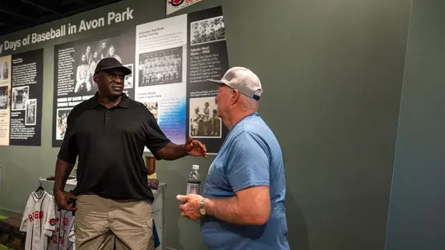 Two men talk in front of the Early Days of Baseball in Avon Park panel.