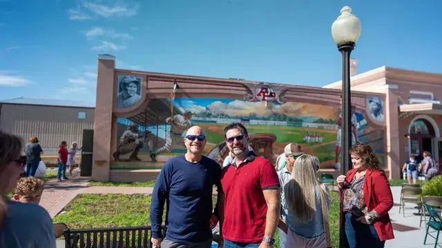 Guests in front of the mural, two men in dark polos in the middle.