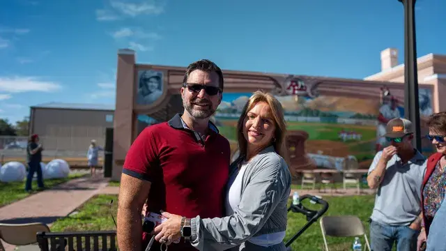 A couple pose in front of the mural's outfield scene.