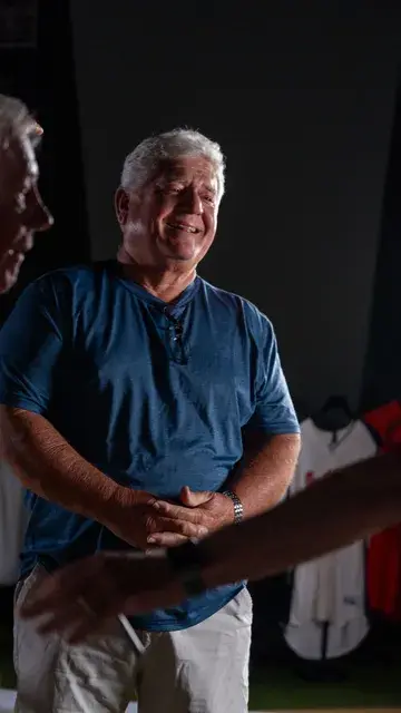 The man in the blue shirt laughs with a visitor.