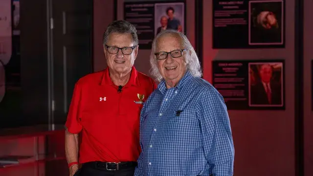 Two men, one in a red polo and one in a blue shirt, pose in the gallery.