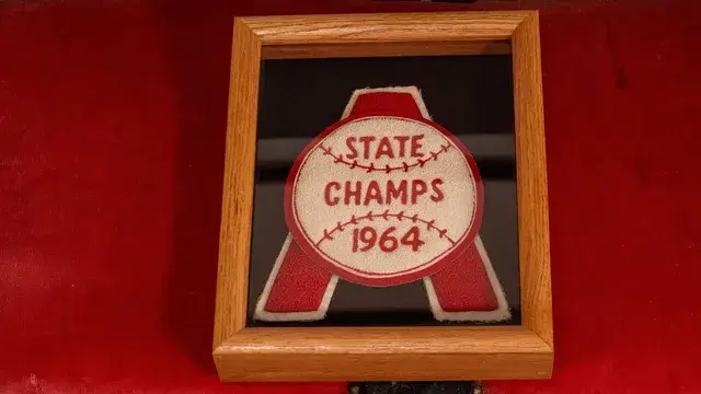 The framed State Champs 1964 patch on red cloth.