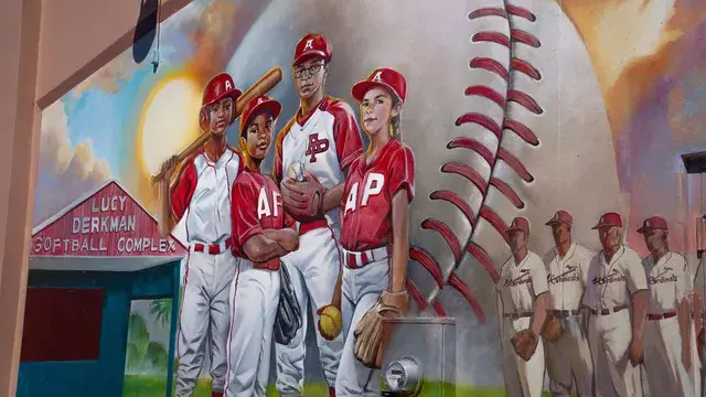 A painted mural of Avon Park players in red and white uniforms beside a giant baseball seam.