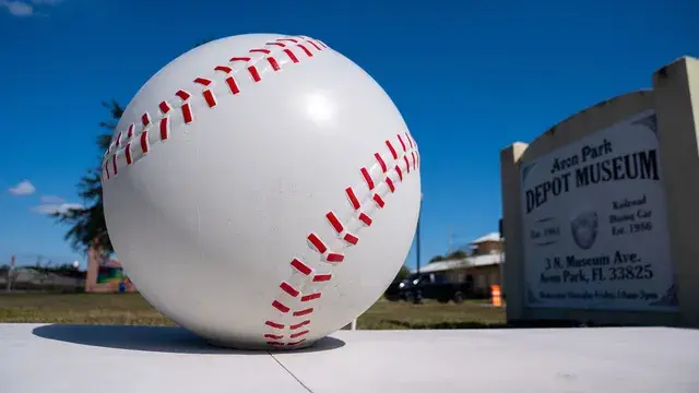 A giant baseball sculpture beside the Avon Park Depot Museum sign.